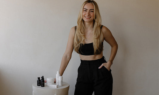 Evara CEO standing next to a white pedestal with Vivant skincare products against a plain wall.